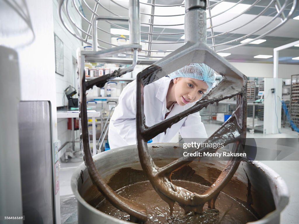 Female worker mixes chocolate in cake factory