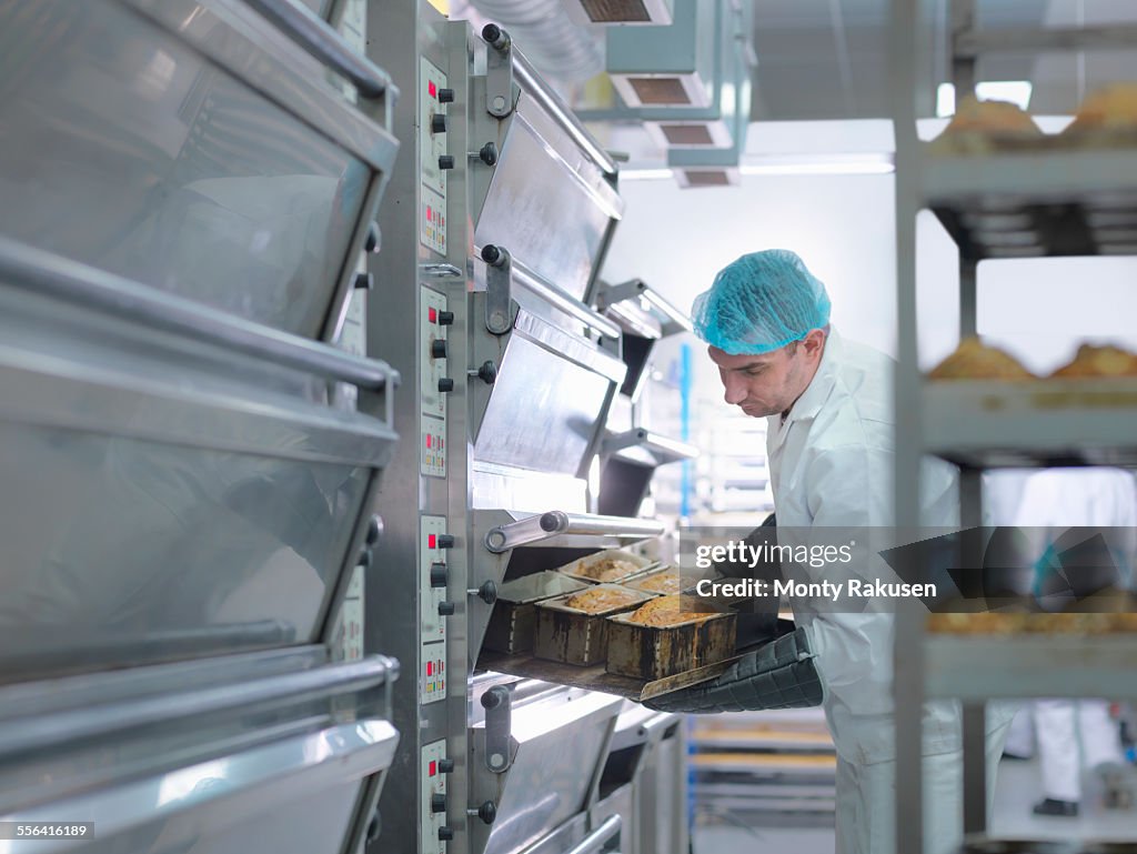 Baker taking cakes out of oven in cake factory