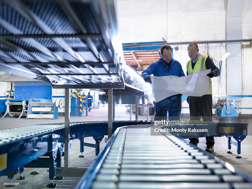 Engineers inspecting new conveyor in engineering factory