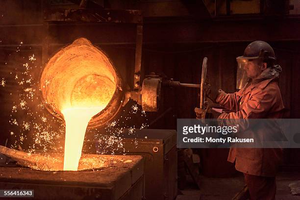 worker pouring molten metal from flask in foundry workshop - molten fotografías e imágenes de stock