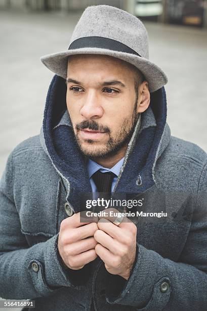 businessman fastening his coat - fedora stock-fotos und bilder