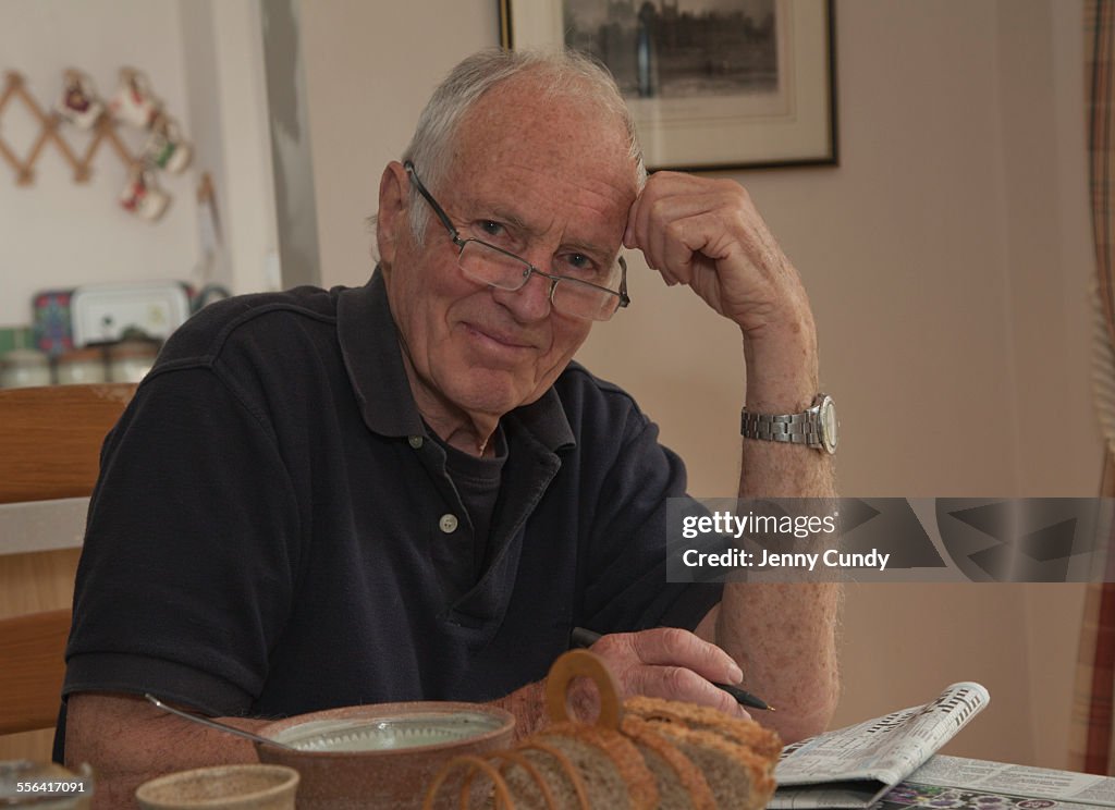 Portrait of senior man, sitting at breakfast table with newspaper