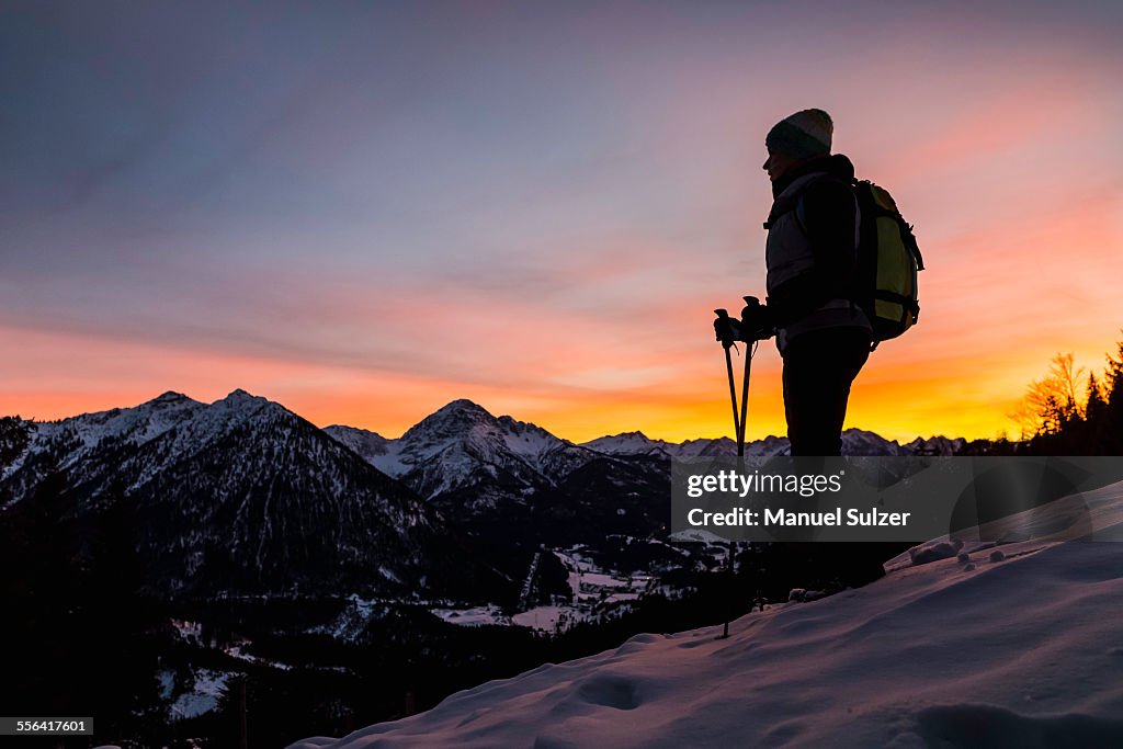 Young female hiker looking out from mountainside at dusk, Reutte, Tyrol, Austria