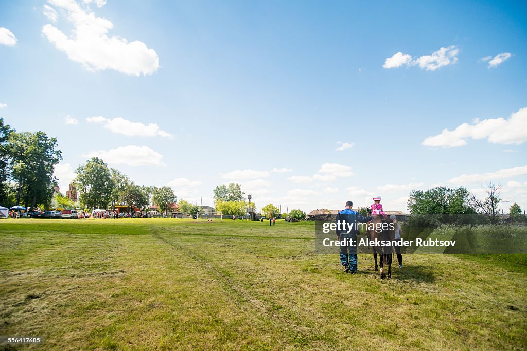 Rear view of young man and two girls riding horse in field, Rezh, Sverdlovsk Oblast, Russia