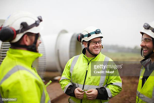 engineers having conversation at wind farm - sports helmet stock-fotos und bilder