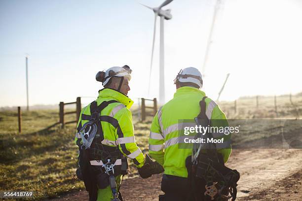 two engineers at wind farm, walking together, rear view - material reflector de seguridad fotografías e imágenes de stock