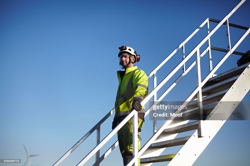 Portrait of engineer on steps, at wind farm