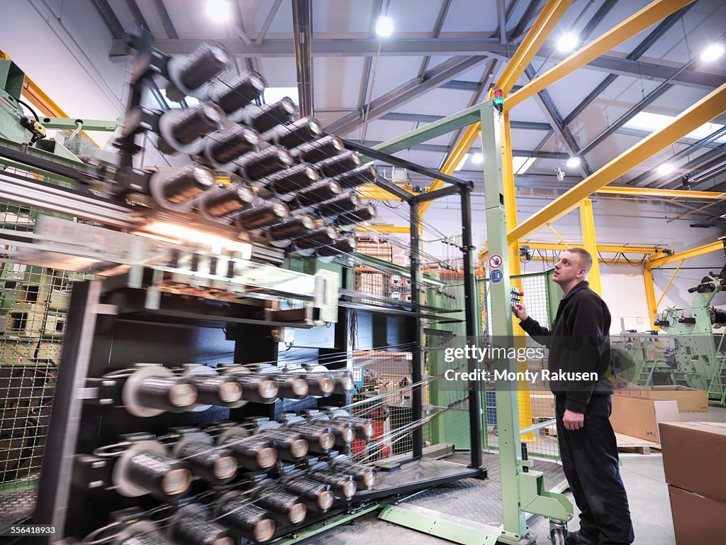 Worker operating carbon fibre loom in carbon fibre factory