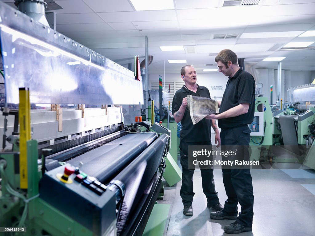 Workers inspecting carbon fibre sample in carbon fibre factory