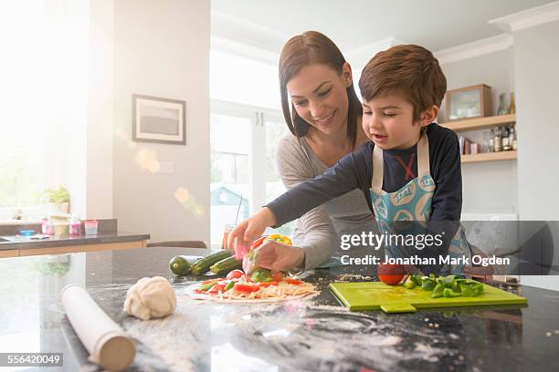 mother and son preparing pizza together in kitchen - day 5 foto e immagini stock