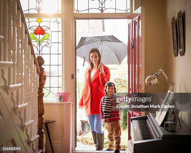 mother and son arriving at front door of home on rainy day, portrait - mother son shower stockfoto's en -beelden