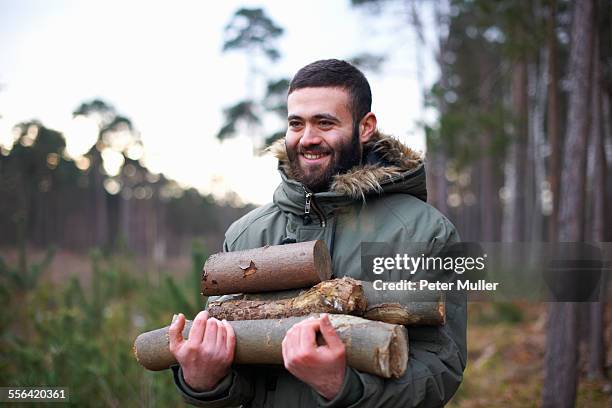 young man collecting logs for campfire in forest - traditional parka stock pictures, royalty-free photos & images