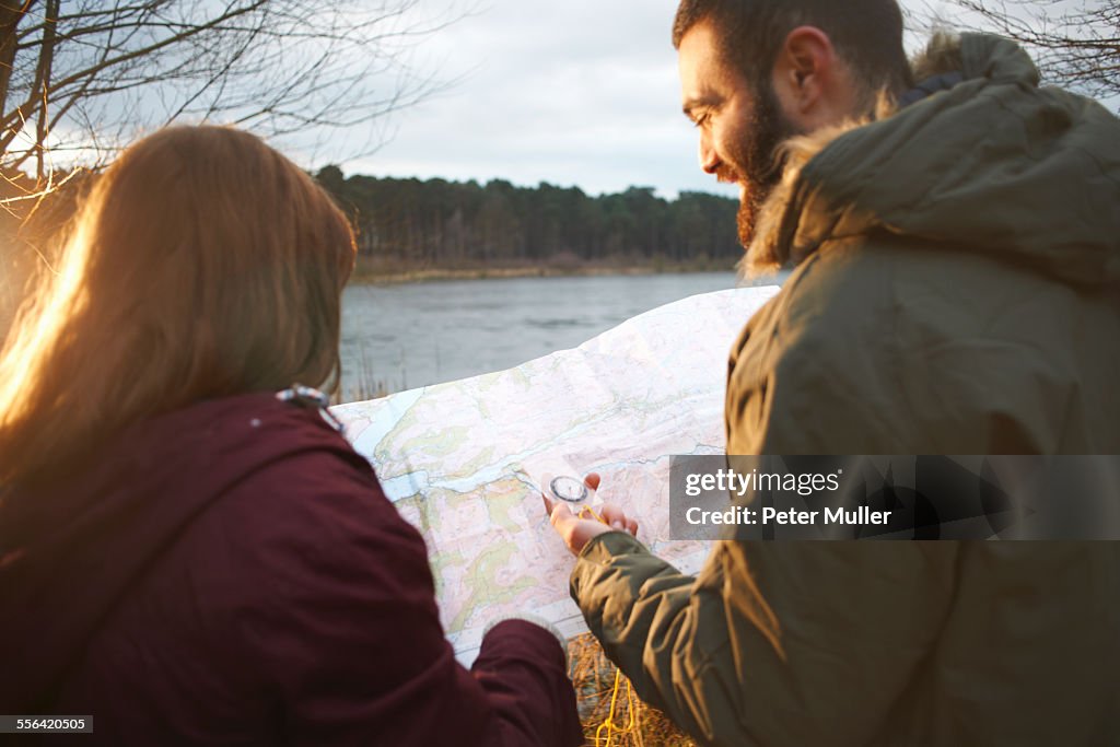 Young couple at lakeside reading map