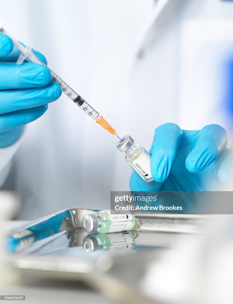 Close up of doctors hands preparing a vaccine to inject patient