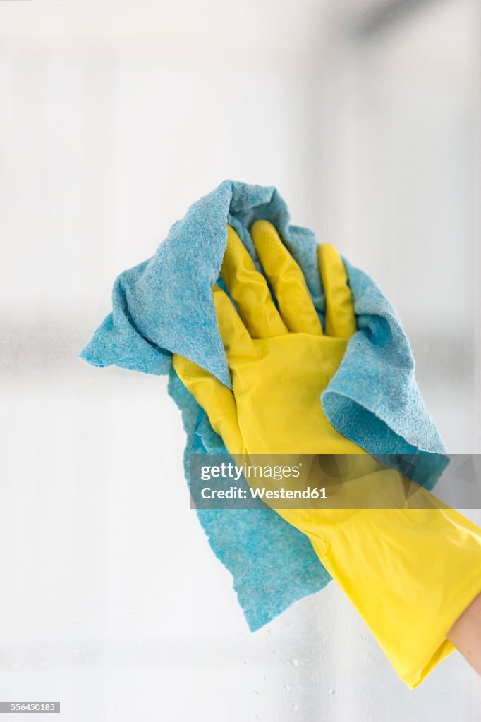 Woman's hand cleaning glass pane