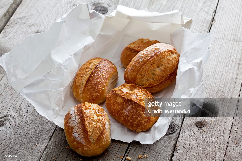 Five bread rolls on paper and grey wood