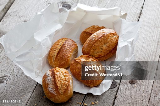 Five bread rolls on paper and grey wood Five bread rolls on paper and grey wood