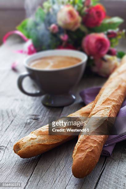 two french baguettes, cup of coffee, bunch of flowers on breakfast table - french baguette stock-fotos und bilder