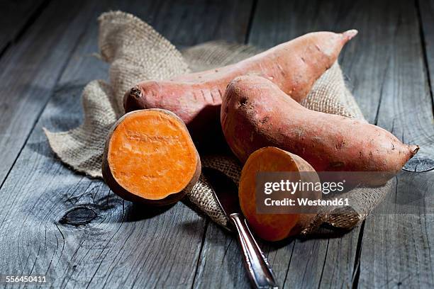 row sweet potatoand knife on jute, wood - zoete aardappel stockfoto's en -beelden