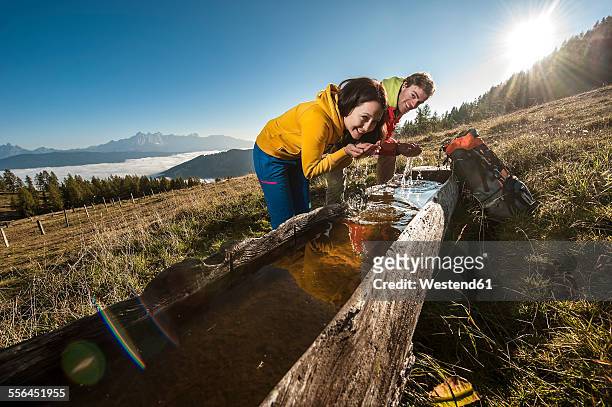 austria, altenmarkt-zauchensee, young couple refreshing at watering place - leaning over stock-fotos und bilder