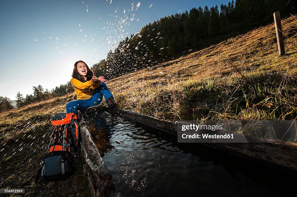 Austria, Altenmarkt-Zauchensee, young woman splashing at watering place