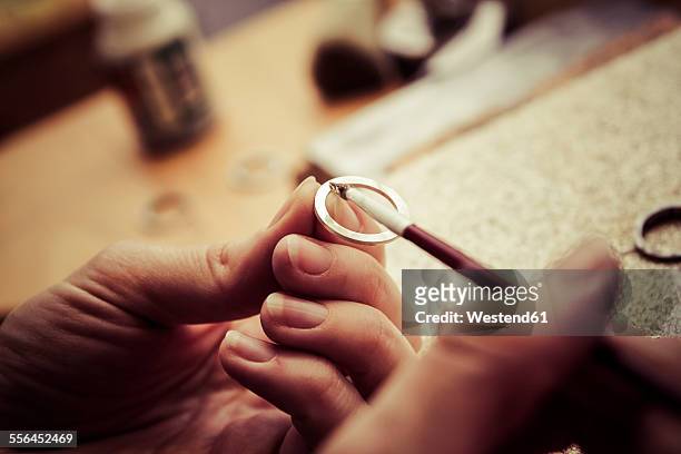 goldsmith working on wedding rings, applying chemical on surface - jewelled stockfoto's en -beelden
