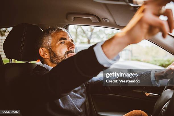 businessman driving car adjusting rear view mirror - rear view mirror stock pictures, royalty-free photos & images