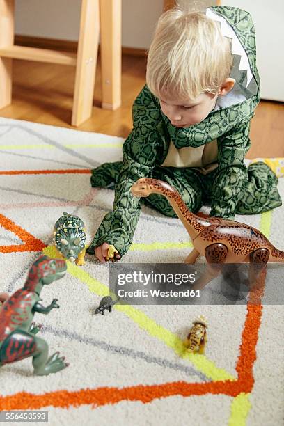 little boy wearing dinosaur costume playing with toy dinosaurs - dinosaur toy i stock pictures, royalty-free photos & images