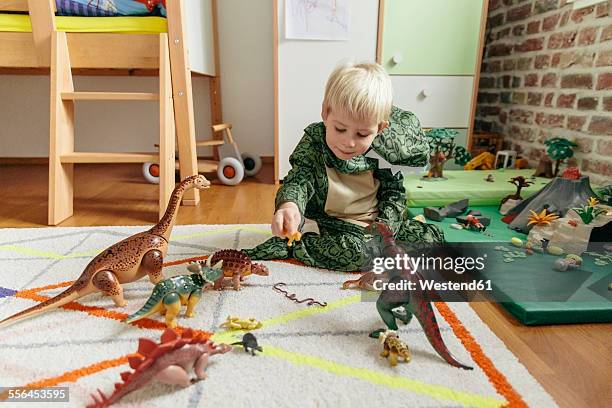 little boy wearing dinosaur costume playing with toy dinosaurs - dinosaur toy i stock pictures, royalty-free photos & images