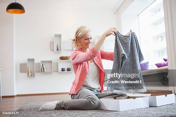 woman with purchase at living room - mid adult woman sweater stock pictures, royalty-free photos & images