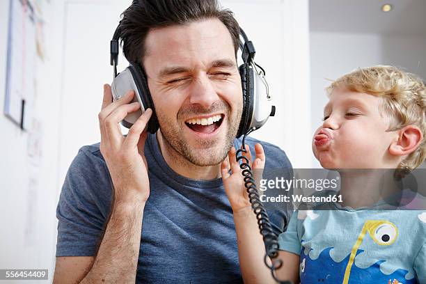 father and son listening to music with headphones - vater sohn musik stock-fotos und bilder