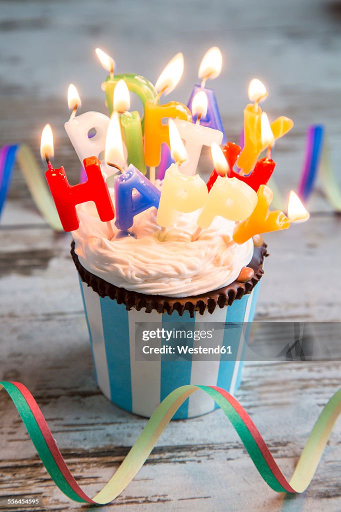 Birthday muffin with chocolate buttons and lighted candles