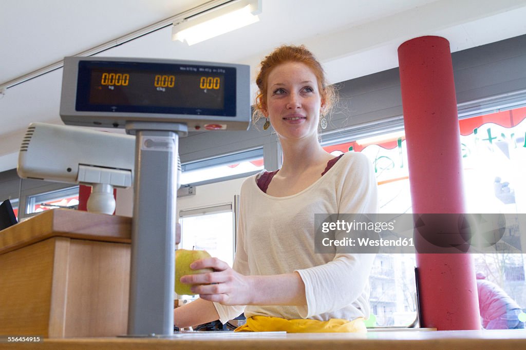 Portrait of smiling young woman sitting at counter of wholefood shop