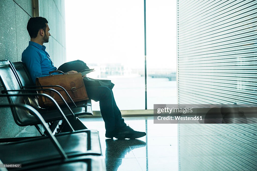 Young businessman at waiting area looking out of window