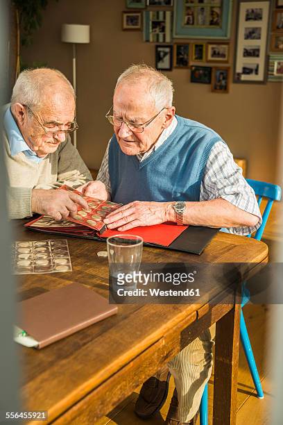 two senior friends with coin album - numismatik stock-fotos und bilder
