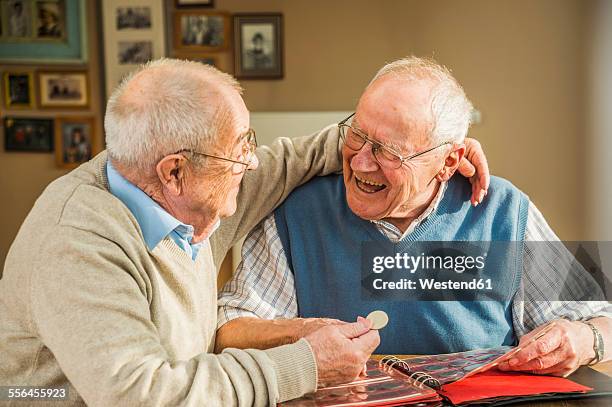 two happy senior friends with coin album - numismatics stock pictures, royalty-free photos & images