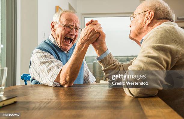 two senior friends arm wrestling - echar un pulso fotografías e imágenes de stock