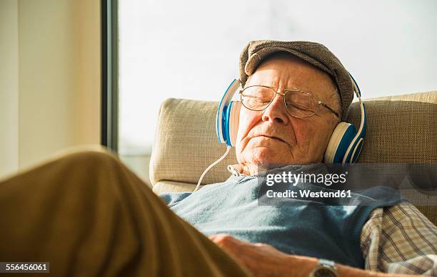 senior man at home relaxing with headphones - man sleeping with cap stock pictures, royalty-free photos & images