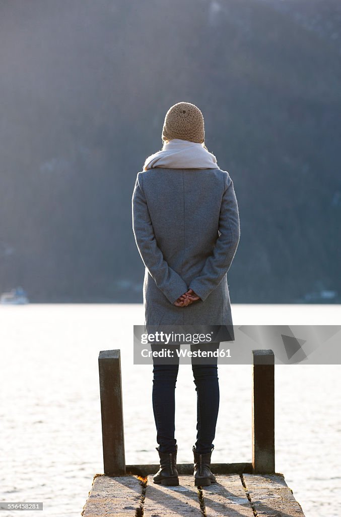 Austria, Mondsee, teenage girl standing on jetty in autumn