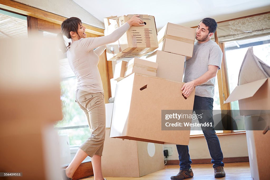 Couple moving house stacking boxes
