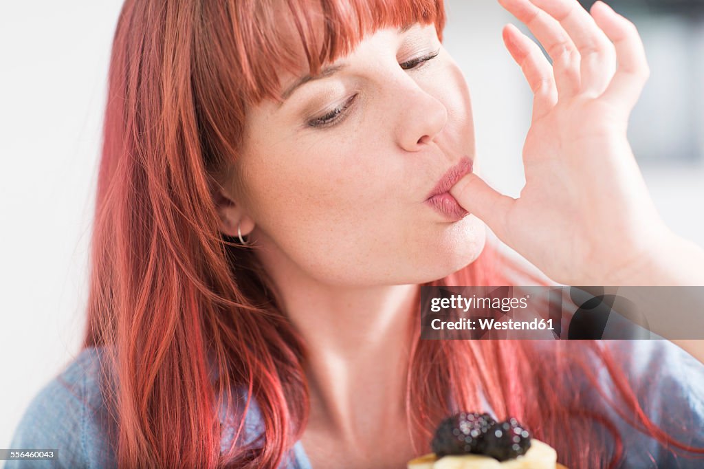 Portrait of young woman licking her finger