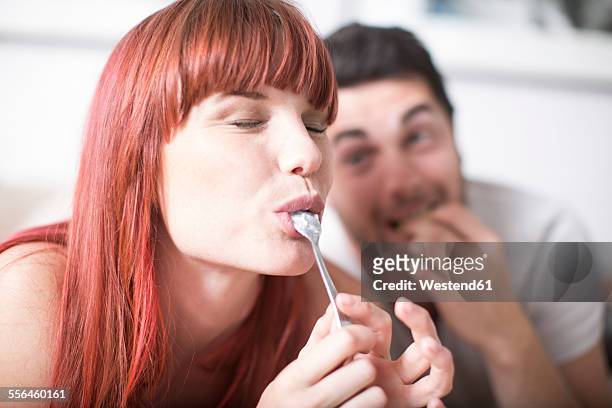 portrait of young woman licking spoon - indulgence foto e immagini stock