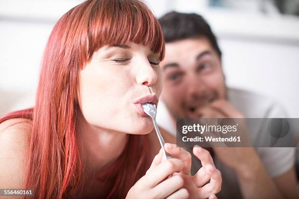 portrait of young woman licking spoon - women licking women stock pictures, royalty-free photos & images