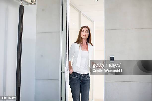 casually dressed businesswoman opening boardroom door - doors of the 21st century ストックフォトと画像
