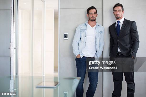 casually and formally dressed twin males in office - eeneiige tweeling stockfoto's en -beelden