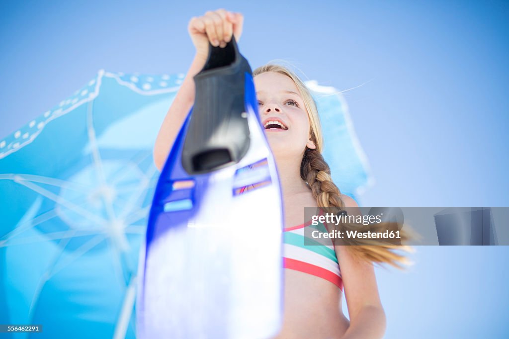 Girl on beach with flippers at sunshade