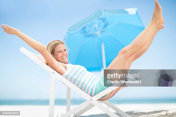 exuberant woman on a beach chair - woman excited sitting chair stock pictures, royalty-free photos & images