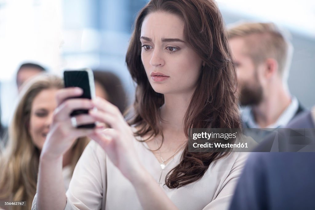 Annoyed woman looking on cell phone in busy city