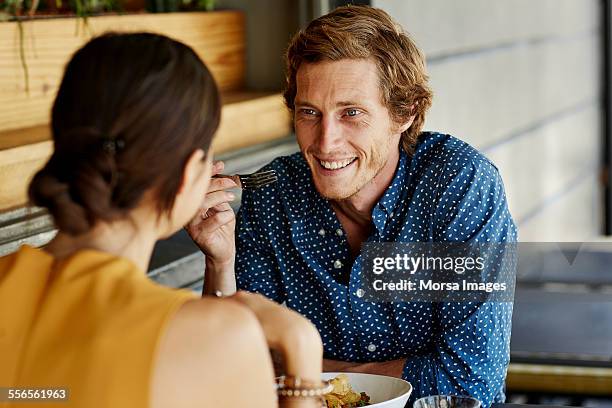 happy man having food with woman at restaurant - sleeveless shirt stock pictures, royalty-free photos & images