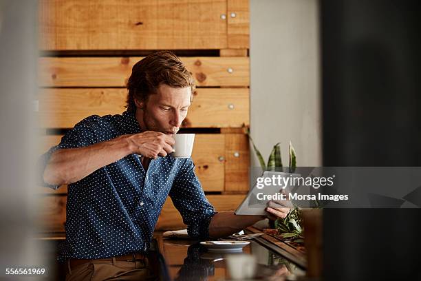 man using tablet pc while having coffee at cafe - coffee cafe stock-fotos und bilder